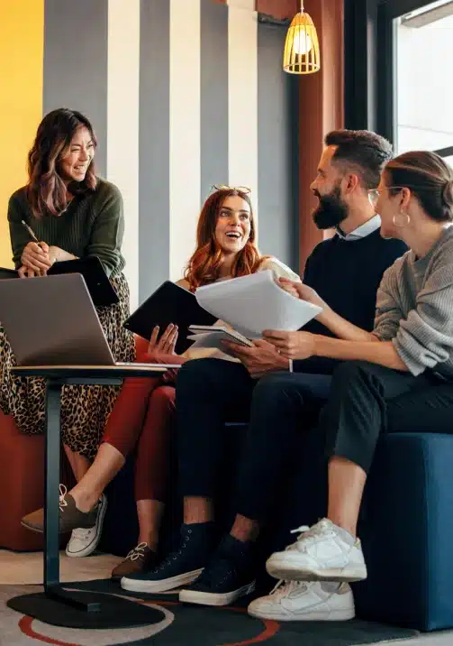 Team of coworkers collaborating together over documents and a laptop