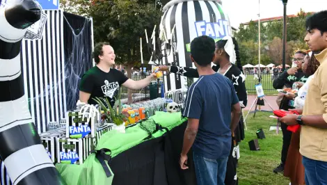Students lining up at a Fanta-branded Halloween activation booth on a college campus lawn