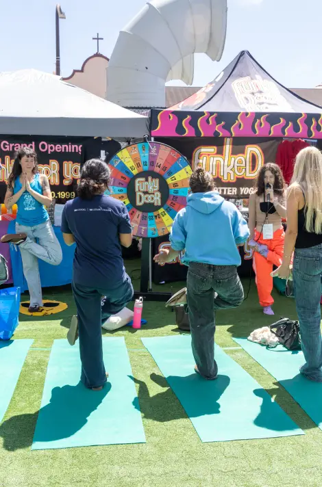 Students doing yoga poses at an outdoor Funky Door branded campus activation with a prize wheel