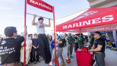 Student doing pull-ups on a bar at a Marines-branded campus recruiting activation