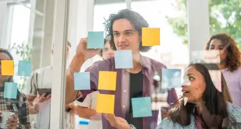 Team collaborating with sticky notes on a glass wall